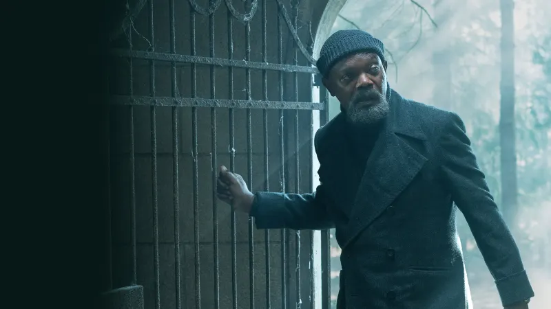 Samuel L. Jackson jako Nick Fury w ciemnym płaszczu i czapce opiera dłoń o metalową bramę, kadr z serialu Tajna inwazja